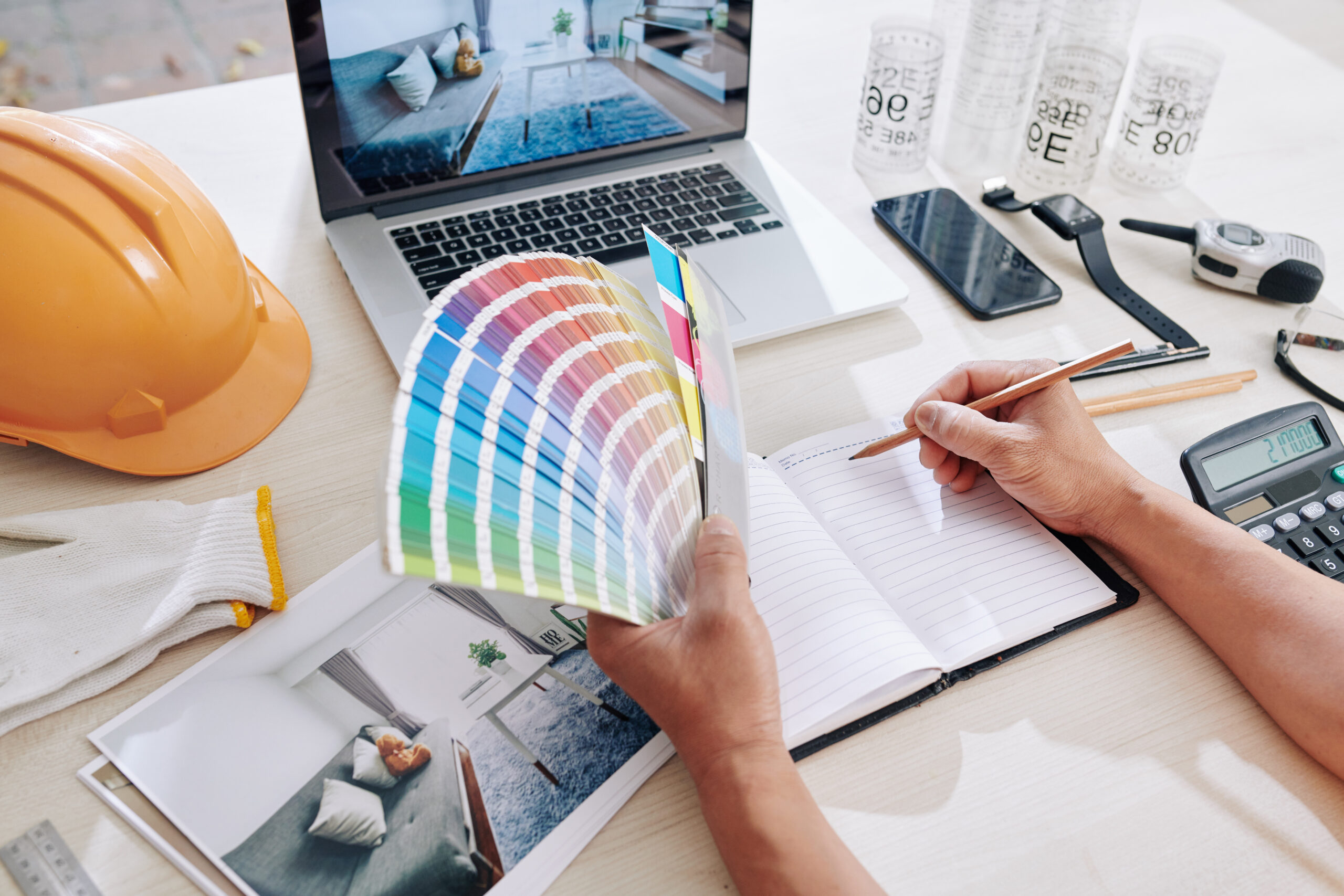 Designer working on color scheme for living room of client and writing ideas in planner